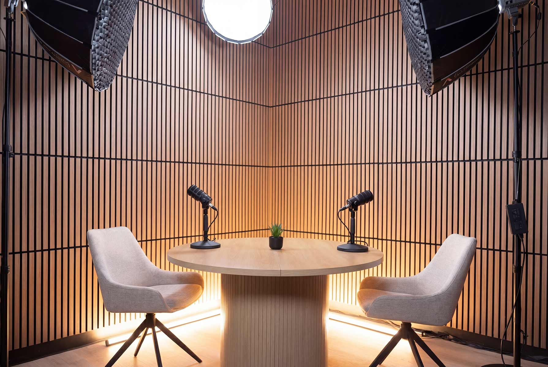 Content Studio interview setup with a round table, two chairs, and slatted wood walls